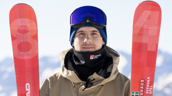 Jesper Tjäder håller i sina skidor på toppen av ett berg.