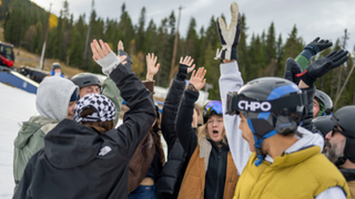 En grupp med åkare och ledare som sträcker upp en hand i luften.